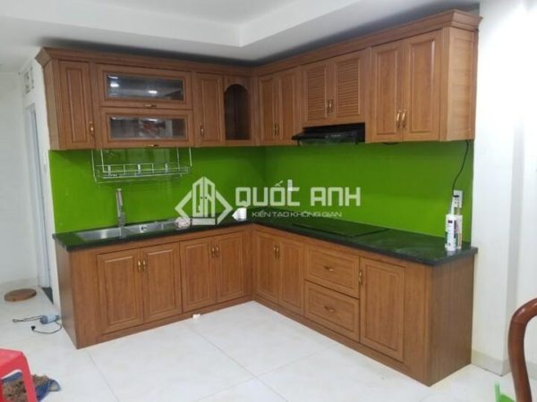 Tủ bếp nhôm giả gỗ kết hợp với kính ốp bếp màu xanh lạ mắt.