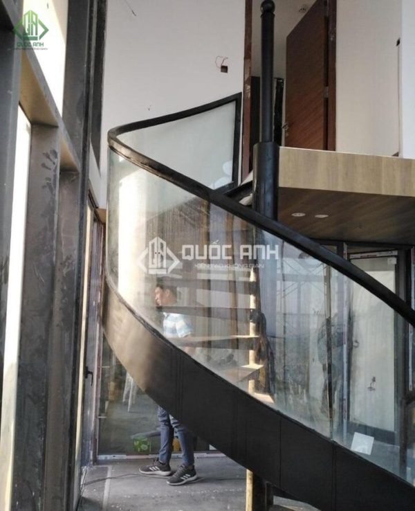Cầu thang kính cong kết hợp tay vịn màu đen cá tính.